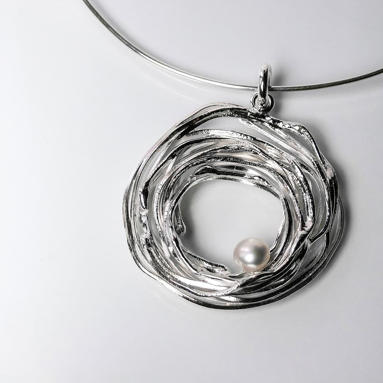 Coiled sterling silver nest pendant set with a freshwater pearl