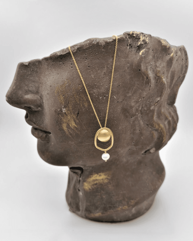 Gold pendant necklace with a pearl drop, shown on a bronze sculpted bust