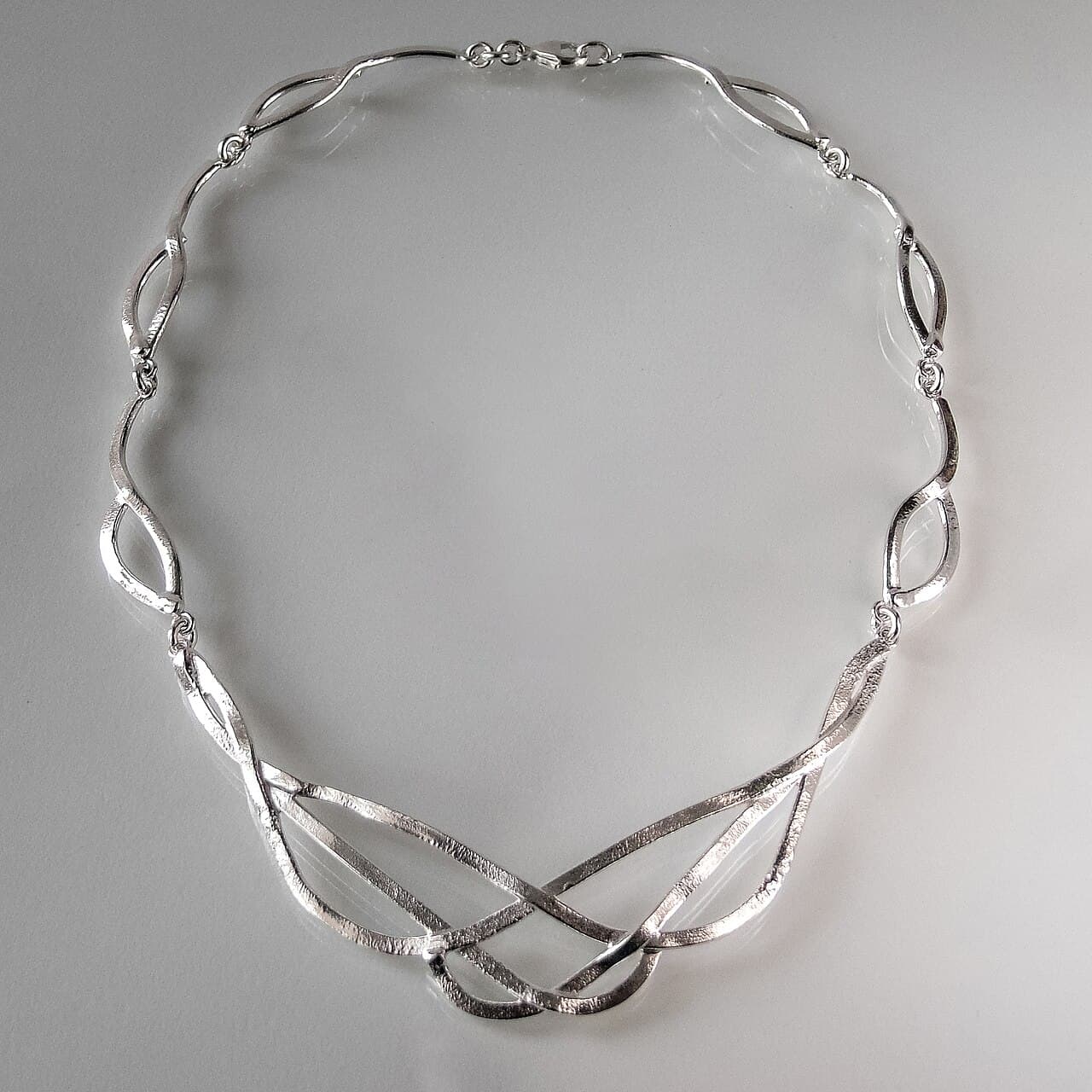 Sterling silver necklace of hand-shaped links, laid flat